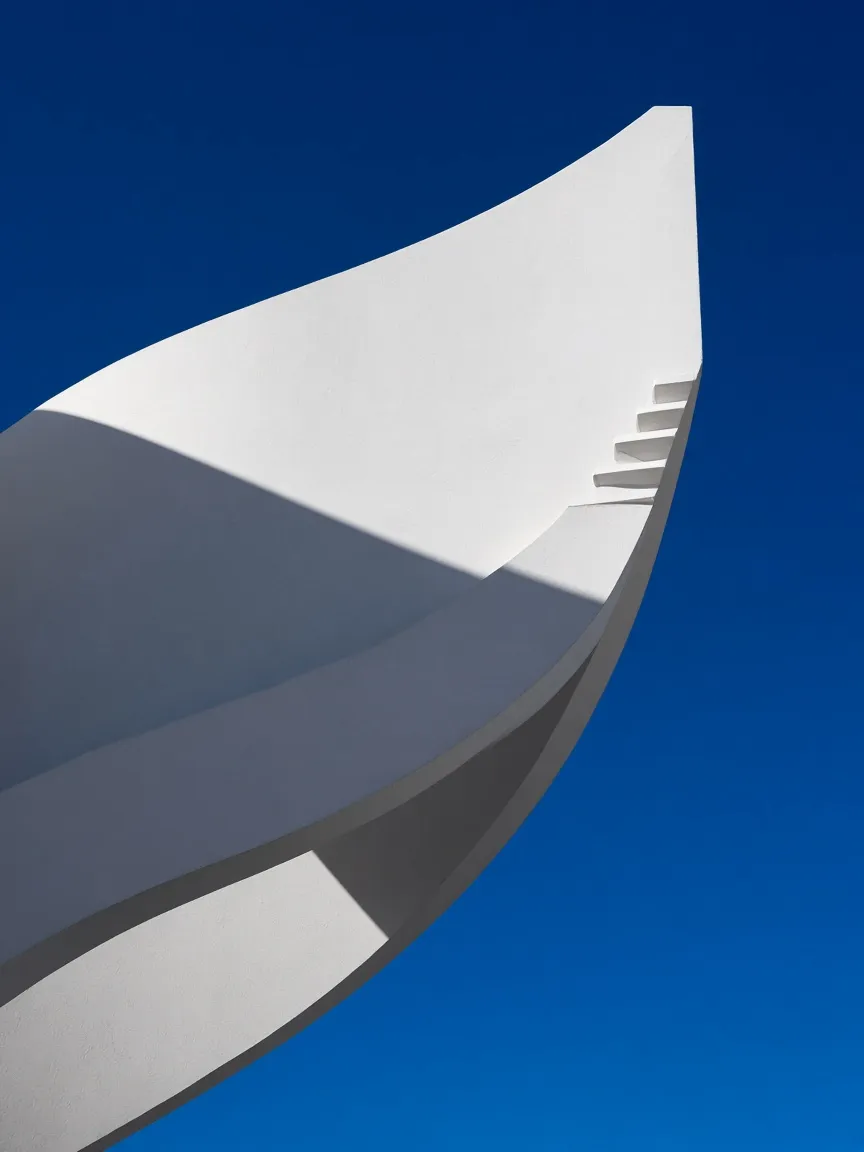 Curved white concrete stair against a deep blue sky